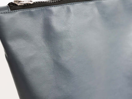 Close-up of the grey faux leather backpack showcasing the smooth texture and zipper closure.