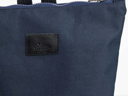 Close-up of a stylish waterproof backpack in navy blue with a leather label and a zipper closure.