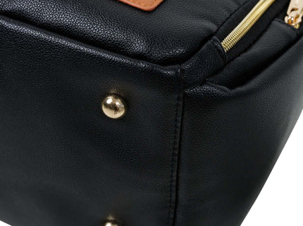 Close-up of a stylish black diaper backpack with gold zippers and a leather logo patch.