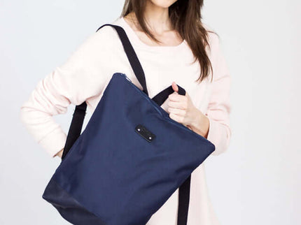 Stylish woman carrying a waterproof backpack with blue leather bottom, perfect for daily essentials.