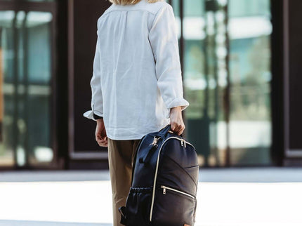 Stylish woman walking with a large diaper backpack in an urban setting, showcasing modern design and functionality.