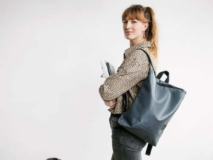 Woman wearing a grey faux leather backpack, stylish and functional for daily use, perfect for work or casual outings.