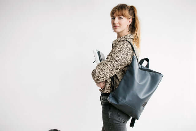 Woman wearing a grey faux leather backpack, stylish and functional for daily use, perfect for work or casual outings.