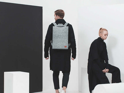 Stylish grey Lund backpack worn by a person, showcasing its minimalist design in a modern setting.