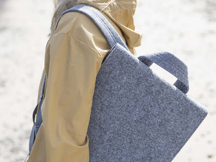 Unisex grey backpack LUND worn by a model at the beach, showcasing its sleek design and practicality for everyday use.