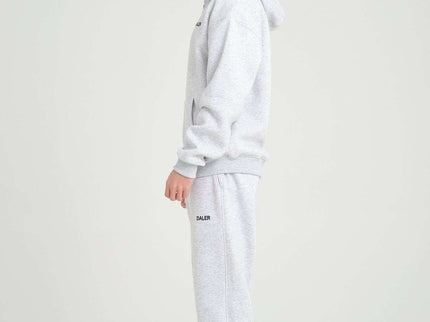 Side view of a male model wearing a grey melange oversized heavyweight zipper hoodie and matching sweatpants.