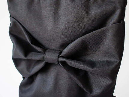 Close-up of a black waterproof backpack featuring a large decorative bow on the back.
