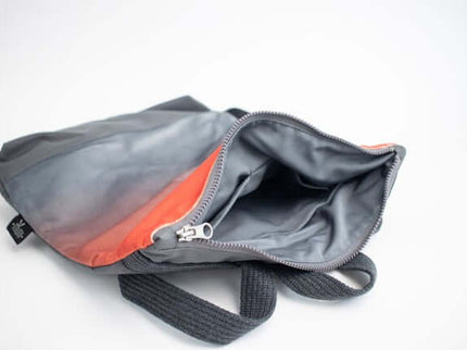 Interior view of a gray and coral faux leather backpack with zipper and straps.