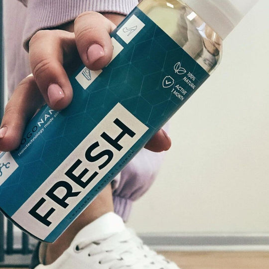 Applying GoGoNano Fresh probiotic spray inside a white sneaker