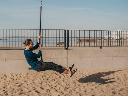 Person enjoying a swing on a sandy beach wearing Märt Black Sandals, showcasing comfort and versatility.