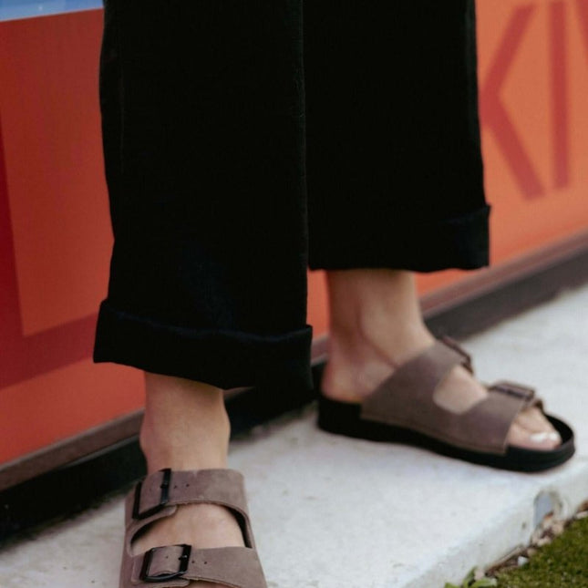 Meeliku women's leather sandals in brown, featuring a stylish design and comfort, worn with black pants.