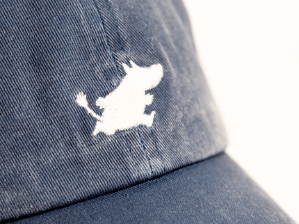 Close-up of a Moomintroll embroidered logo on a blue denim cap, showcasing playful Nordic design and stylish craftsmanship.
