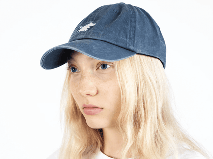 Moomintroll washed denim cap in blue on a model with long blonde hair, showcasing adjustable fit and playful design.