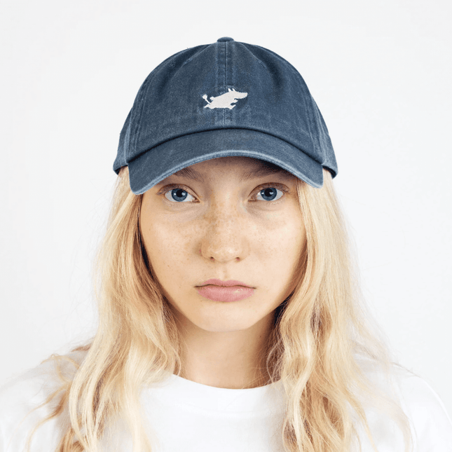 Moomintroll washed denim adult cap in blue worn by a model with blonde hair, featuring playful embroidery design.