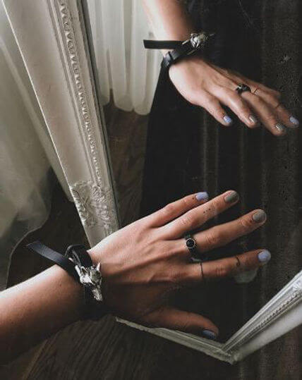 Double wrap wolf buckle leather bracelet showcased on a hand in front of a mirror, emphasizing bold fashion accessories.